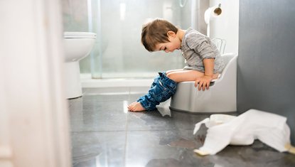 פעוט בן שנתיים יושב על סיר רגע חיובי בתהליך של גמילה מחיתולים והקניית הרגלי היגיינה