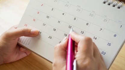 יד נשית מחזיקה עט מעל לוח שנה שבוע 1 להריון שלב התכנון והמעקב אחרי תחילת ההיריון