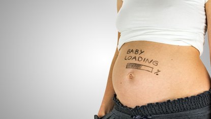 בטן של אישה בשבוע 27 עם שלט 'טוען תינוק' – שילוב של הומור וציפייה בסוף החודש השישי