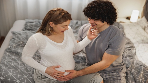 זוג מחבק בטן הריונית בבית שבוע 28 להריון שלב מתקדם עם בדיקות והכנות ללידה