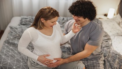 זוג מחבק בטן הריונית בבית שבוע 28 להריון שלב מתקדם עם בדיקות והכנות ללידה