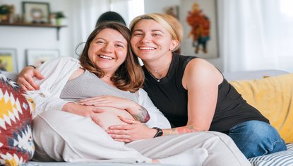 אישה בהריון מחייכת לצד דולה תומכת – ליווי מקצועי רגשי ופיזי לקראת לידה